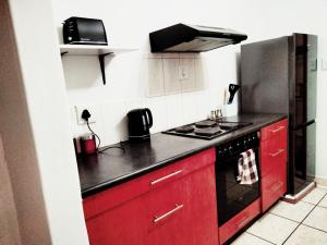 a kitchen with red cabinets and a stove top oven at Apartment on MR103 in Mbabane