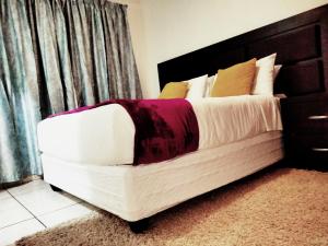 um quarto com uma cama branca e uma cabeceira preta em Apartment on MR103 em Mbabane