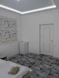 um quarto branco com uma cama e um quadro na parede em MAR.s em Bukhara