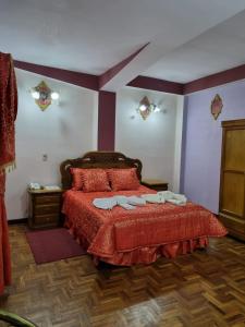 a bedroom with a red bed with two towels on it at HOTEL SAMARICUSUN in Potosí