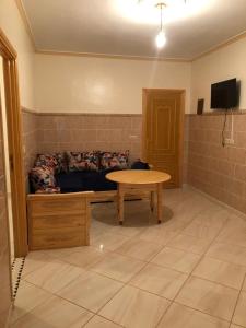 uma sala de estar com uma mesa e um sofá em Residence al Rahma 03 em Monte ʼArrouit