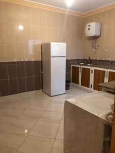 uma cozinha com um frigorífico branco num quarto em Residence al Rahma 03 em Monte ʼArrouit