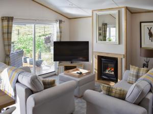 Plumbland的住宿－Beaumont Lodge，带沙发、电视和壁炉的客厅