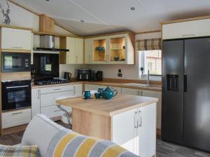 Plumbland的住宿－Beaumont Lodge，厨房配有白色橱柜和黑色冰箱。