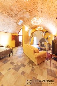 een grote woonkamer met een bank en een plafond bij La Grotta nel Fienile in Lari