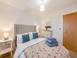 een slaapkamer met een bed met een witte sprei en blauwe kussens bij Sandpiper Rest - Uk46781 in Ellington