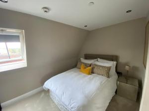 a bedroom with a white bed with pillows and a window at Beautiful Penthouse in centre of Winchester in Winchester +8 photos