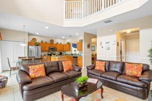 a living room with two leather couches and a kitchen at Be-Our-Guest Home! 15 mins to Disney! in Kissimmee