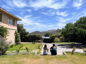 mężczyzna i kobieta siedzący na trawie przed domem w obiekcie Hostería La Viña w mieście La Cumbre