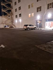 a car parked in a parking lot next to a building at فندق روزميلون in Al Fayşalīyah