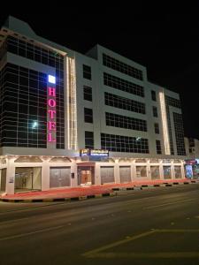 a large building with a neon sign on it at فندق روزميلون in Al Fayşalīyah