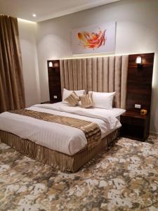 a bedroom with a large bed with a large headboard at فندق روزميلون in Sakakah