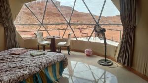 een slaapkamer met een groot raam met uitzicht op de woestijn bij Sultan Luxury Camp in Wadi Rum