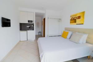 Casas Novas Guesthouse - Adults Only في لاغوس: غرفة نوم بيضاء مع سرير أبيض مع وسائد صفراء