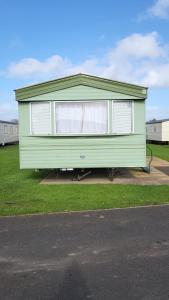 a green house sitting on the side of a road at Caravan near Port Carlisle in Aikton