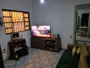 sala de estar con TV de pantalla plana y sofá en Casa para Temporada Agrishow 2024 en Ribeirão Preto