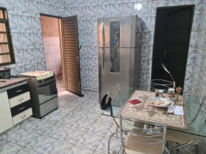 eine Küche mit einem Kühlschrank aus Edelstahl und einem Tisch in der Unterkunft Casa para Temporada Agrishow 2024 in Ribeirão Preto