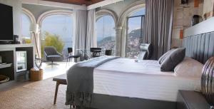 a bedroom with a large bed and large windows at De Cantera Y Plata Hotel Boutique in Taxco de Alarcón