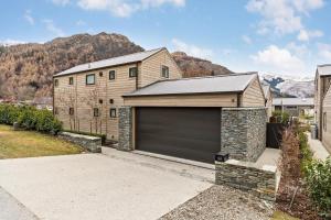 a house with a garage with a mountain in the background at Arrowtown Mountain Views in Arrowtown