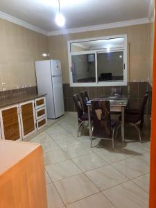 a kitchen with a table and chairs and a refrigerator at Residence al Rahma 02 in Monte ʼArrouit