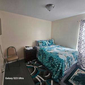 - une petite chambre avec un lit et une chaise dans l'établissement Room K Divine Villa and Resorts 5mins to EWR Airport and 4mins to Penn Station Newark, New York, à Newark