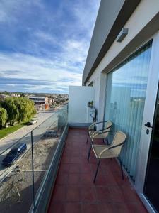 a balcony with two chairs and a view of a street at BRISApartament a cuadras del mar, moderno y confortable in Puerto Madryn +24 photos