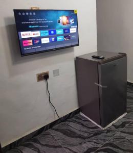 a flat screen tv on a wall with a refrigerator at A Cosy Room and a Parlor-Self in Ikeja
