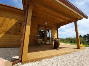 a porch of a wooden cabin with a chair at Quinta dos Mangues in São Martinho do Porto