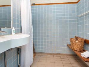 y baño de azulejos azules con lavabo y ducha. en Two-Bedroom Holiday home in Aabenraa 4, en Løjt