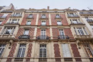 a tall brick building with windows and balconies at Petites chambres rénovées 2024 Paris 17e in Paris