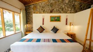 um quarto com uma cama num quarto com uma parede de pedra em Sapa Eco Homestay em Sapa