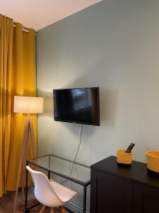 メスにあるCozy studio Metzの壁にテレビと椅子、テーブルが備わる客室です。
