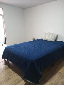 ein Bett mit blauer Bettdecke und zwei Kissen darauf in der Unterkunft Casa de Cristal-Retiros Esenciales Costa Rica in Cartago