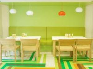 a dining room with tables and chairs and green walls at Hotel AMADA Infinity Near Delhi Airport By LA CASA in New Delhi