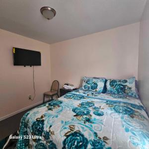 Schlafzimmer mit einem Bett mit blauer Blumenbettdecke in der Unterkunft Room G DIVINE VILLA AND RESORT, 6 MINS TO AIRPORT, 4MINS TO PENN STATION. in Newark