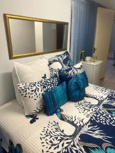 - un lit avec des oreillers bleus et blancs et un miroir dans l'établissement Triple T Guest house, à Johannesbourg