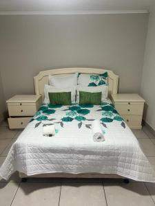 - une chambre dotée d'un lit blanc avec des oreillers verts et bleus dans l'établissement Triple T Guest house, à Johannesbourg