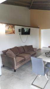 a living room with a couch and a tv on the wall at Location Liliane in Bouillante