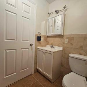 uma casa de banho com um WC branco e um lavatório. em Room J Divine Villa and Resorts 5mins to EWR Airport and 4mins to Penn Station Newark, New York em Newark