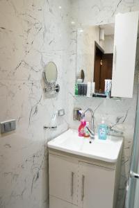 Baño blanco con lavabo y espejo en شقة فندقية مفروشة, en Ḩulwān
