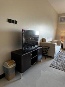 ein Wohnzimmer mit einem Flachbild-TV und einem Sofa in der Unterkunft شقة 2 غرفة نوم وصالة بدخول ذكي in Chamis Muschait