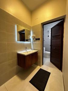 ein Badezimmer mit einem Waschbecken, einem Spiegel und einem WC in der Unterkunft شقة 2 غرفة نوم وصالة بدخول ذكي in Chamis Muschait