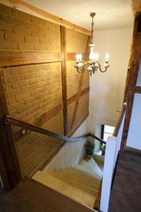 a staircase with a chandelier next to a brick wall at Pension Alte Schmiede in Zabeltitz