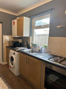 a kitchen with a sink and a washing machine at Amazing Ground Floor one bedroom apartment Forest Road in London