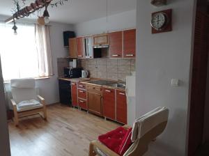 a kitchen with wooden cabinets and a clock on the wall at Gdańsk Mieszkanie parter Marine in Gdańsk