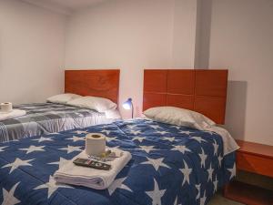 1 dormitorio con 2 camas y edredón azul y blanco en YURAQ WASI Hotel/Restobar en Huánuco