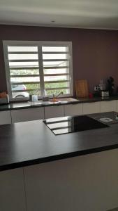 a kitchen with a counter top and two windows at Bas de villa Noumea in Noumea