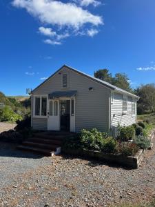 a small house with a porch and a driveway at Ohariu Farm Cottage in Johnsonville