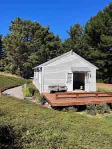 a small white building with a wooden deck at Ohariu Farm Cottage in Johnsonville