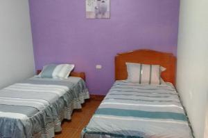 - 2 lits dans une chambre aux murs violets dans l'établissement Casa Hospedaje Aromas, à Tarapoto